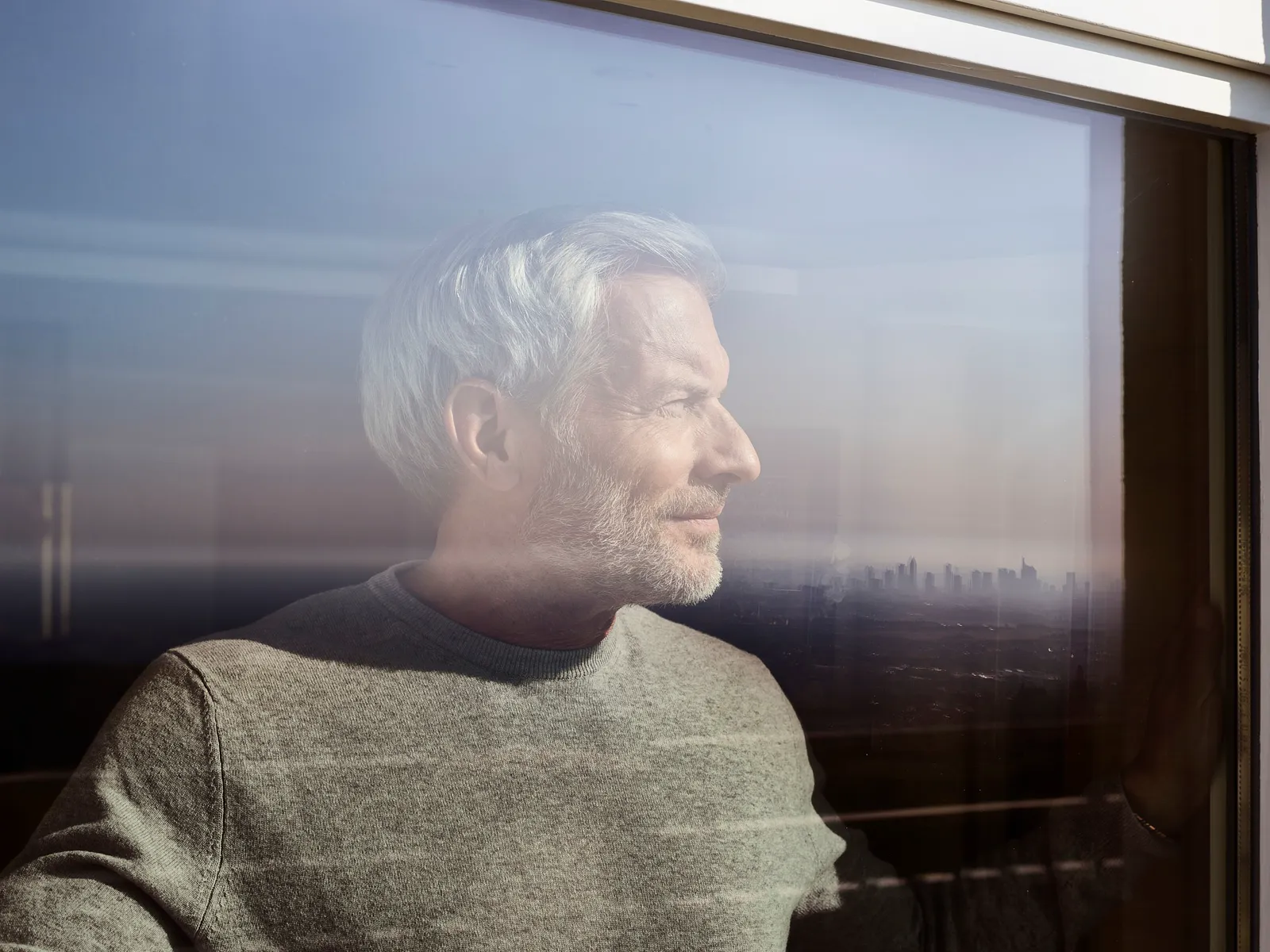Älterer Gast schaut seitlich aus dem Fenster seines Zimmers