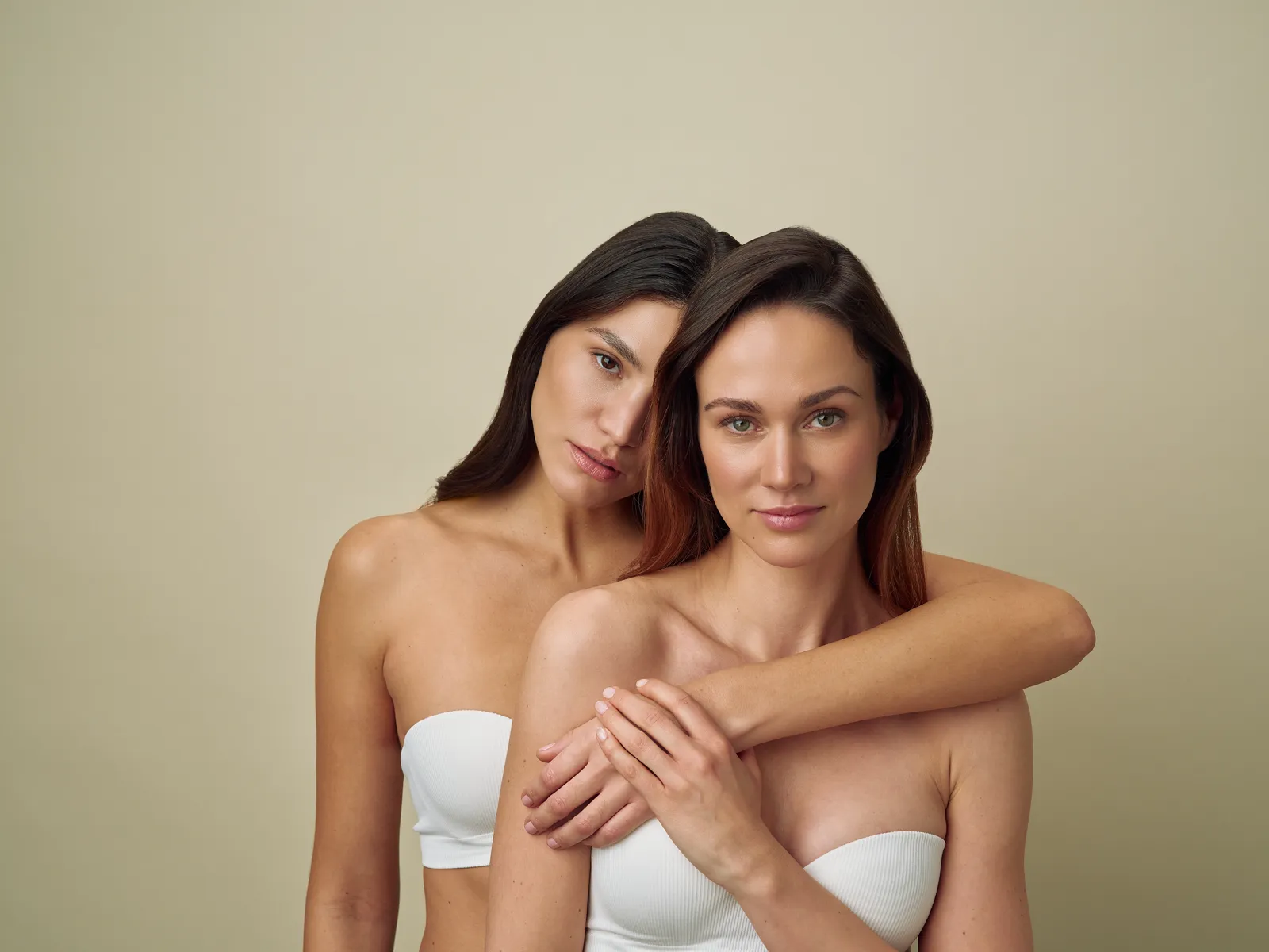 Zwei Models in inniger Umarmung vor warmem beigem Studiohintergrund
