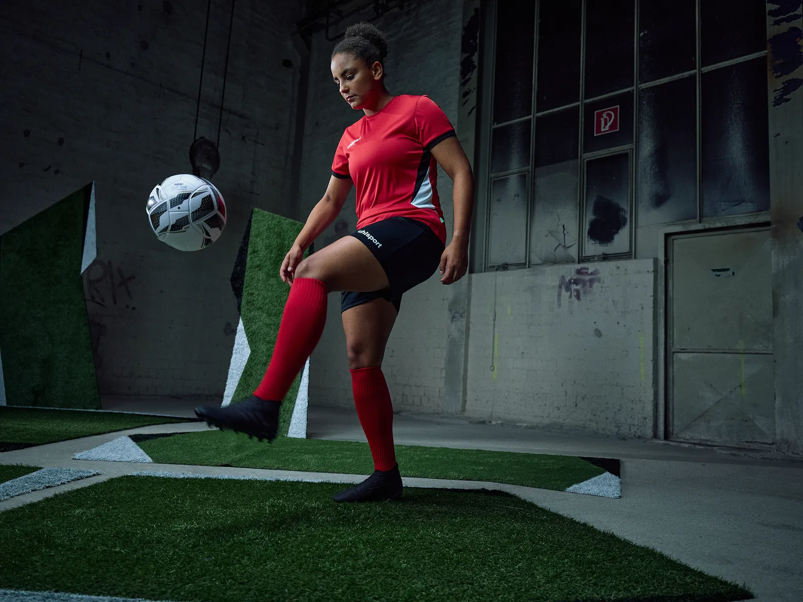 Spielerin im roten Trikot jongliert den Ball in der Halle